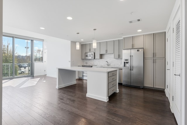 kitchen with a kitchen island, backsplash, stainless steel appliances, dark hardwood / wood-style floors, and pendant lighting