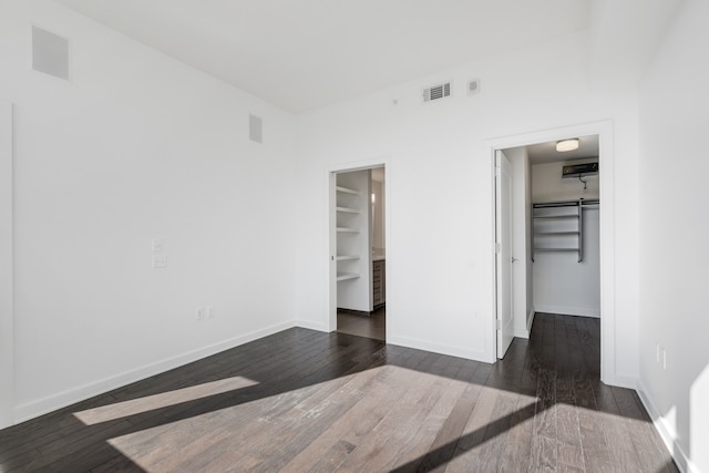 unfurnished bedroom featuring dark wood-type flooring, a closet, and a walk in closet