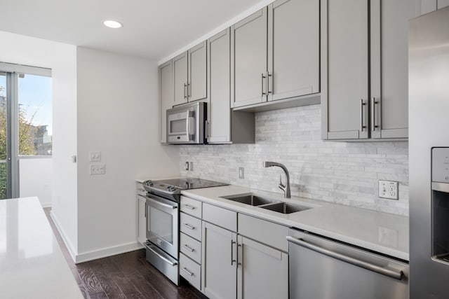 kitchen featuring gray cabinetry, dark hardwood / wood-style floors, backsplash, appliances with stainless steel finishes, and sink