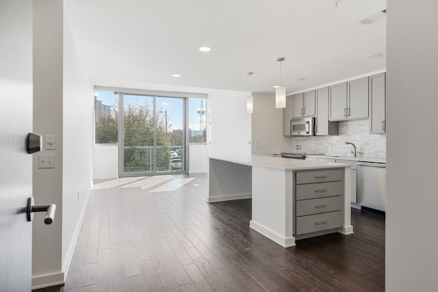 kitchen featuring gray cabinetry, dark hardwood / wood-style floors, backsplash, stainless steel appliances, and a kitchen island