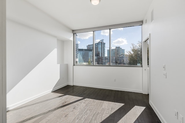 unfurnished room with dark hardwood / wood-style flooring