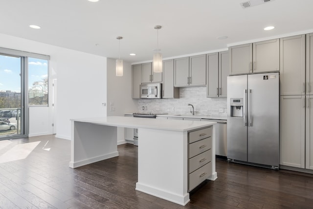 kitchen with dark hardwood / wood-style flooring, a center island, tasteful backsplash, and stainless steel appliances