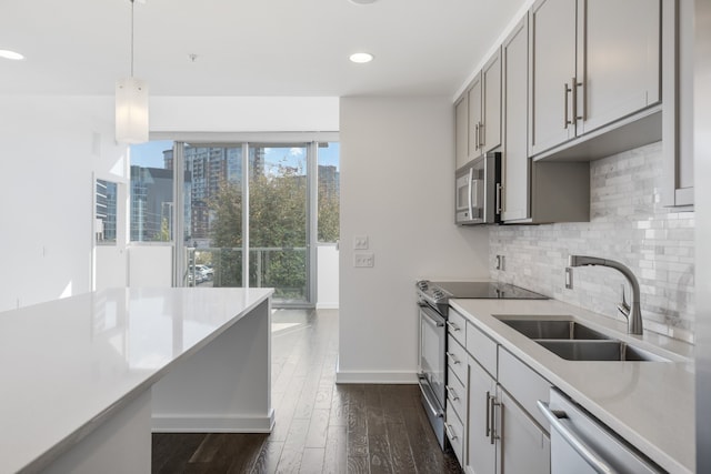 kitchen featuring decorative light fixtures, dark hardwood / wood-style flooring, stainless steel appliances, sink, and tasteful backsplash