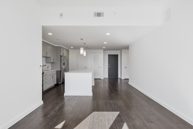 kitchen featuring a kitchen island, dark hardwood / wood-style flooring, stainless steel appliances, and backsplash