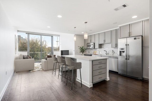 kitchen with a kitchen island, appliances with stainless steel finishes, dark hardwood / wood-style flooring, and gray cabinets