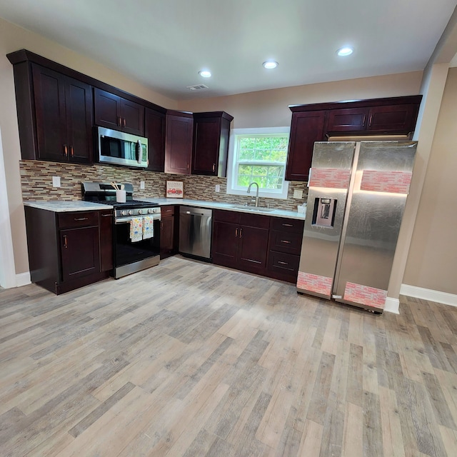 kitchen featuring light hardwood / wood-style floors, appliances with stainless steel finishes, and backsplash