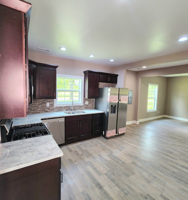 kitchen featuring appliances with stainless steel finishes, sink, tasteful backsplash, light hardwood / wood-style floors, and dark brown cabinetry