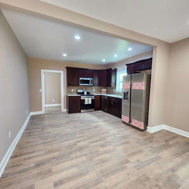 kitchen with appliances with stainless steel finishes, sink, light hardwood / wood-style floors, backsplash, and dark brown cabinets