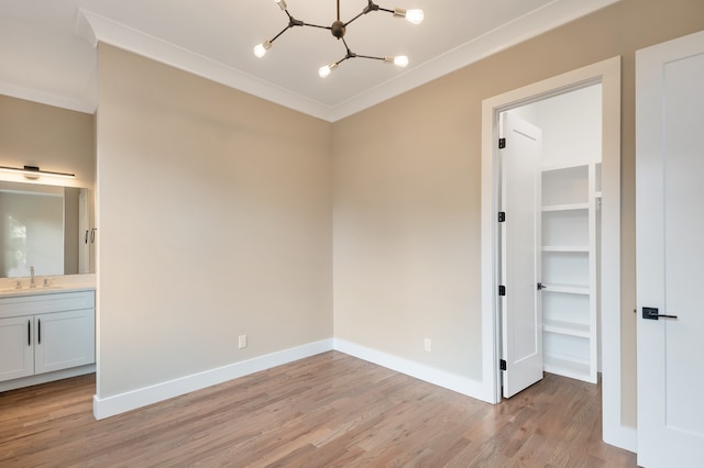 interior space with ensuite bathroom, light wood-type flooring, ornamental molding, an inviting chandelier, and sink