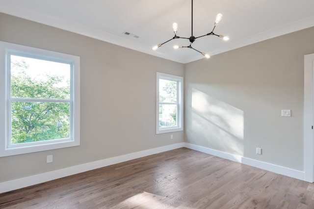 spare room with a chandelier, crown molding, and light wood-type flooring