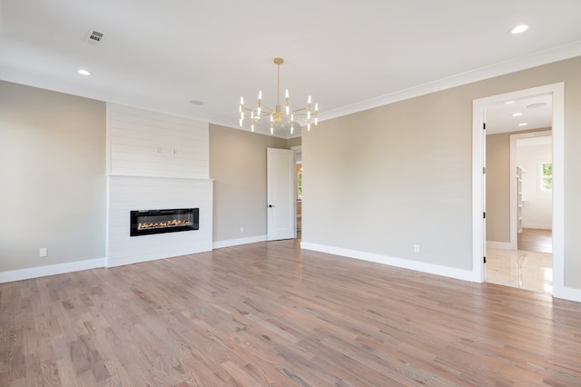 unfurnished living room featuring a fireplace, light hardwood / wood-style floors, brick wall, and a chandelier