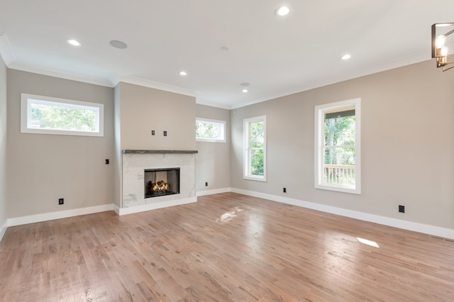 unfurnished living room with ornamental molding, light wood-type flooring, and a fireplace