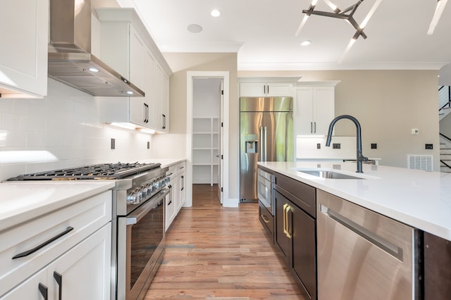 kitchen with built in appliances, backsplash, light hardwood / wood-style flooring, wall chimney range hood, and sink