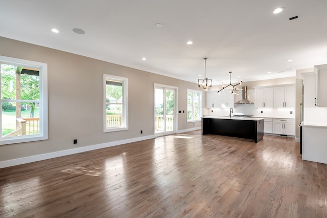 unfurnished living room with sink, crown molding, dark hardwood / wood-style flooring, and a notable chandelier