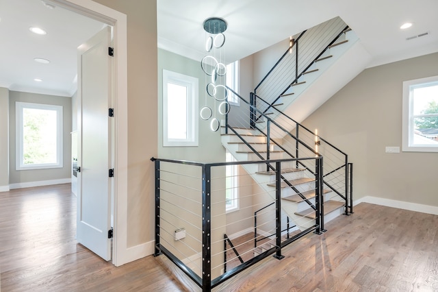 stairway with ornamental molding and wood-type flooring