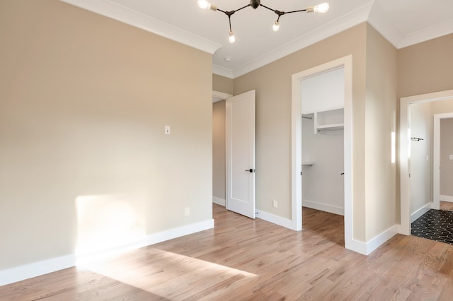 unfurnished bedroom featuring ornamental molding, a closet, a spacious closet, and light wood-type flooring