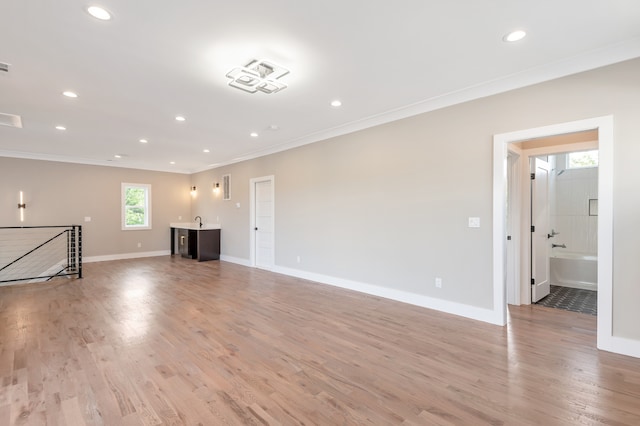 unfurnished living room with hardwood / wood-style floors and crown molding