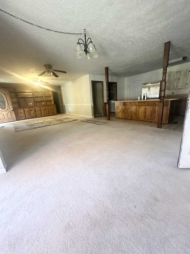 basement featuring light colored carpet, a textured ceiling, and ceiling fan with notable chandelier