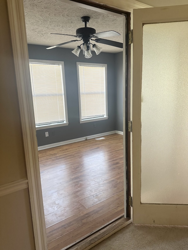 unfurnished room with a textured ceiling, light hardwood / wood-style floors, and ceiling fan