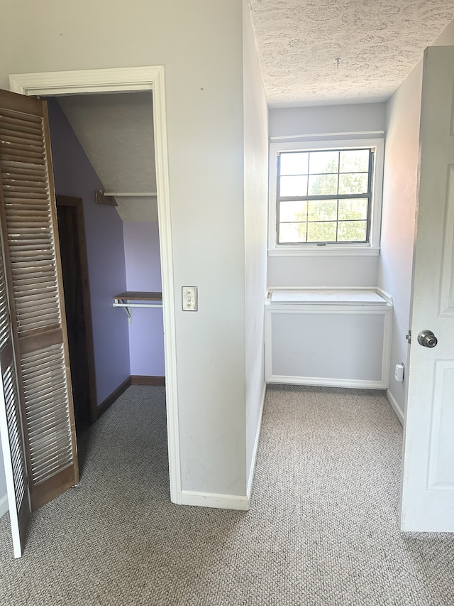 hall with light carpet and a textured ceiling