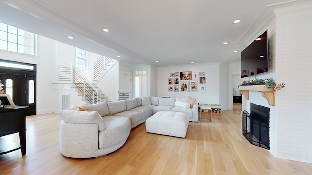 living room with brick wall, ornamental molding, and light hardwood / wood-style floors