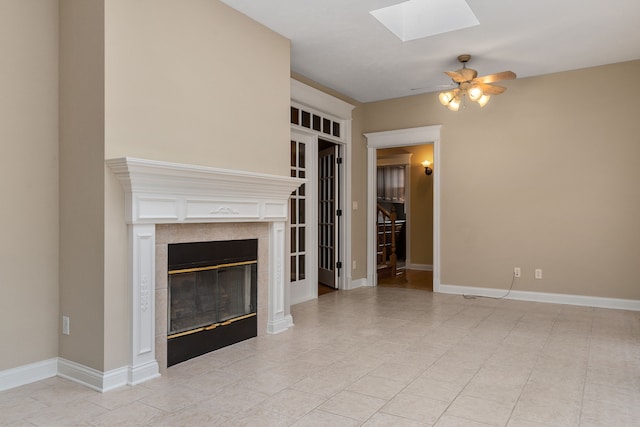 unfurnished living room featuring a skylight, light tile patterned floors, and ceiling fan