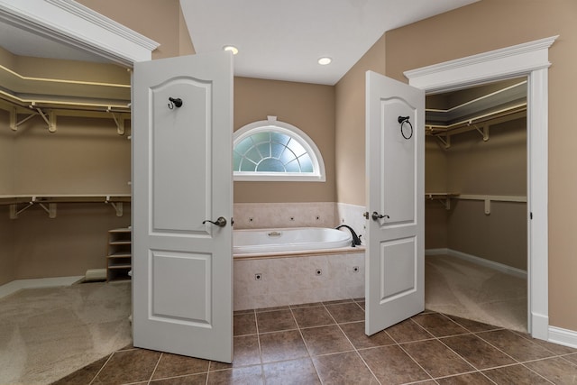 bathroom featuring tile patterned flooring and a relaxing tiled tub