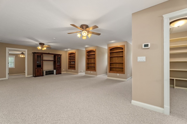 unfurnished living room with built in features, carpet floors, and ceiling fan