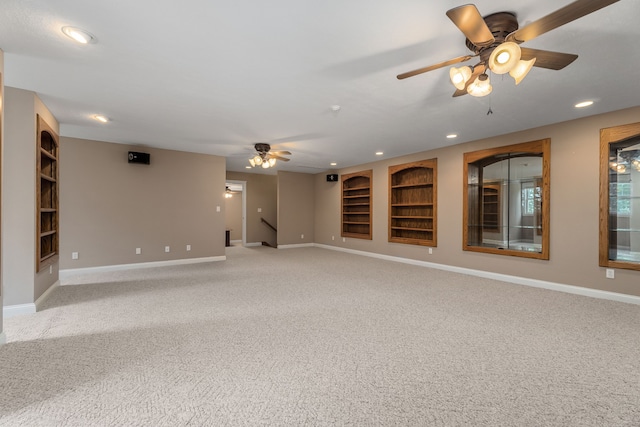 unfurnished room with built in features, carpet, and ceiling fan