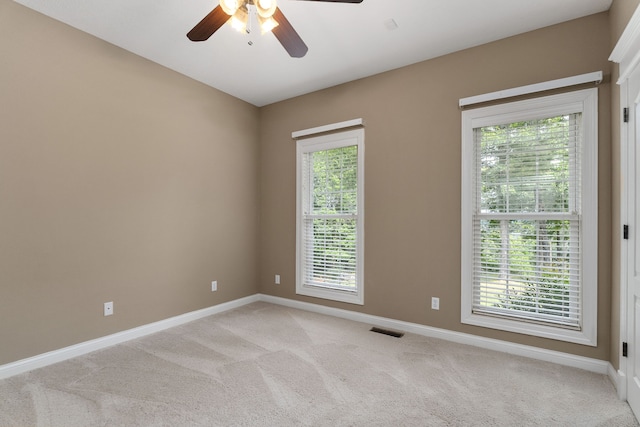 carpeted empty room with a wealth of natural light and ceiling fan