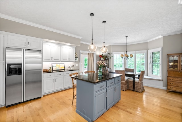 kitchen with a kitchen island, white cabinets, stainless steel built in fridge, light hardwood / wood-style flooring, and pendant lighting