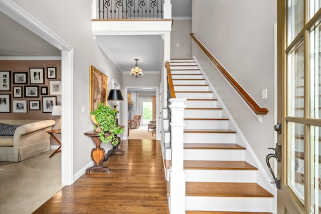 staircase featuring dark hardwood / wood-style flooring, crown molding, and a chandelier