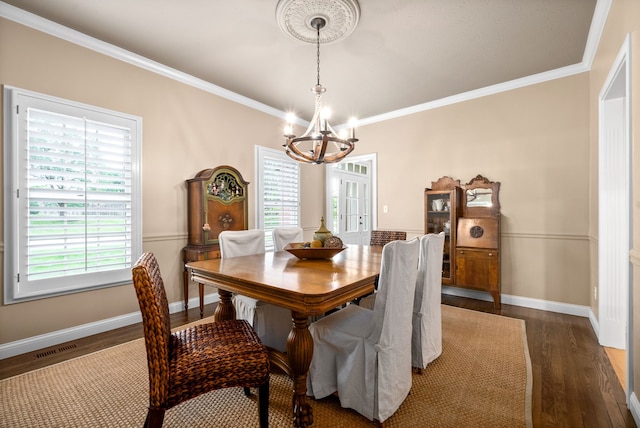 dining space with ornamental molding, hardwood / wood-style floors, and a chandelier