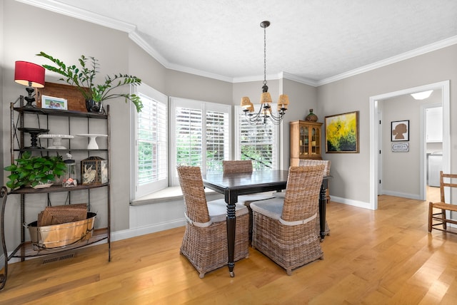 dining space with light wood-type flooring, crown molding, a notable chandelier, washer / dryer, and a textured ceiling