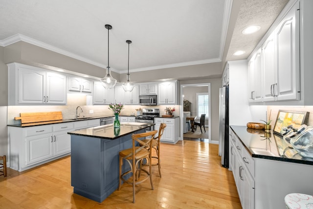 kitchen with light hardwood / wood-style floors, a center island, white cabinetry, and appliances with stainless steel finishes