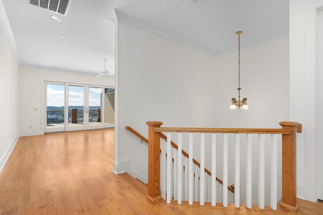 hallway with a chandelier, light hardwood / wood-style flooring, and crown molding