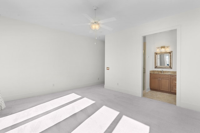 unfurnished bedroom featuring light carpet, ensuite bath, ceiling fan, and sink