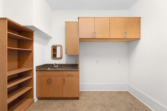 kitchen featuring dark stone countertops, sink, and light colored carpet