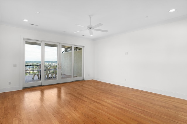 empty room with ceiling fan, light hardwood / wood-style flooring, crown molding, and french doors