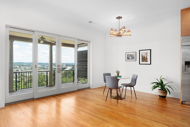 dining room featuring plenty of natural light, light hardwood / wood-style floors, crown molding, and ceiling fan with notable chandelier