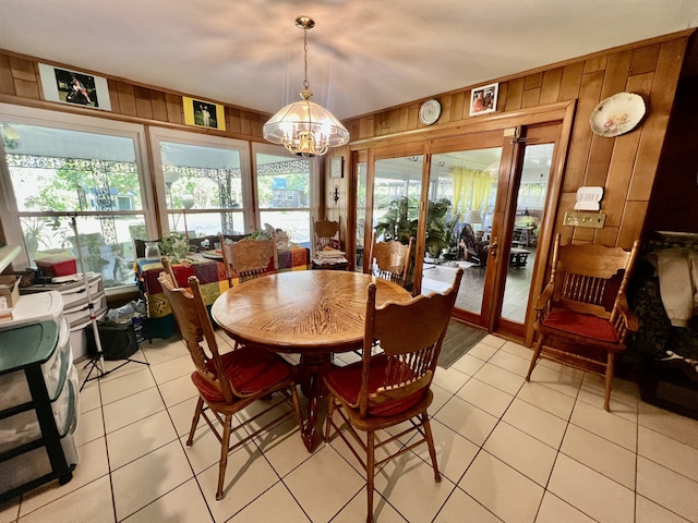 tiled dining room featuring wooden walls and a notable chandelier