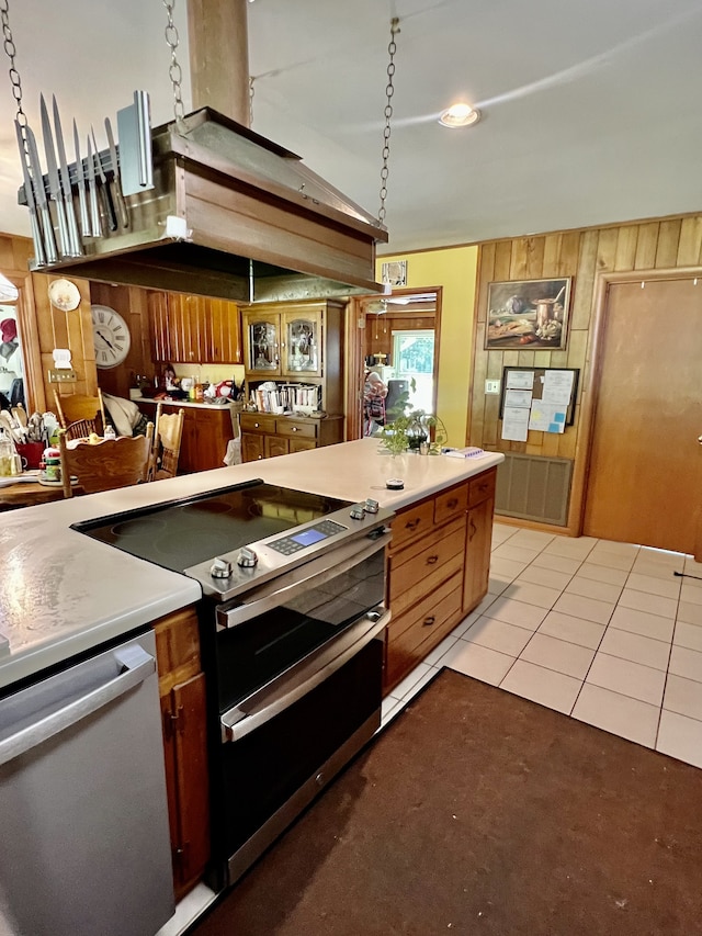 kitchen featuring wooden walls, pendant lighting, light carpet, and stainless steel appliances