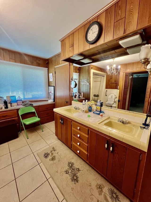 bathroom featuring tile flooring, oversized vanity, double sink, and an inviting chandelier