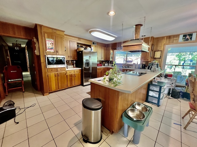 kitchen with light tile floors, custom exhaust hood, sink, stainless steel appliances, and kitchen peninsula