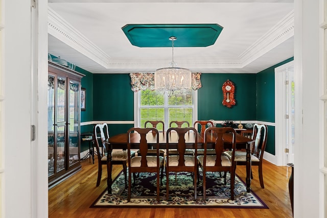 dining area featuring a notable chandelier, ornamental molding, hardwood / wood-style floors, and a tray ceiling