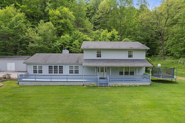 back of property featuring a deck, a lawn, and a trampoline