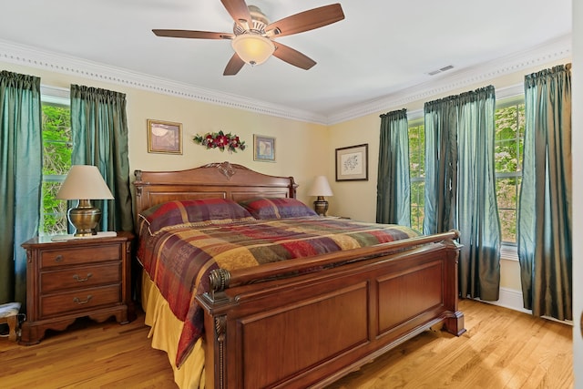 bedroom featuring light hardwood / wood-style floors, multiple windows, ornamental molding, and ceiling fan