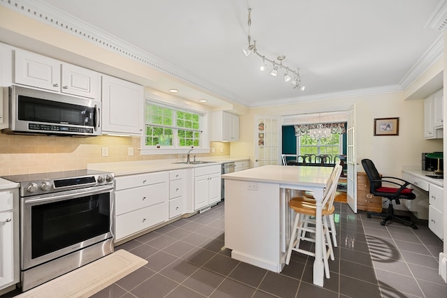 kitchen with a breakfast bar, white cabinets, appliances with stainless steel finishes, dark tile patterned flooring, and sink