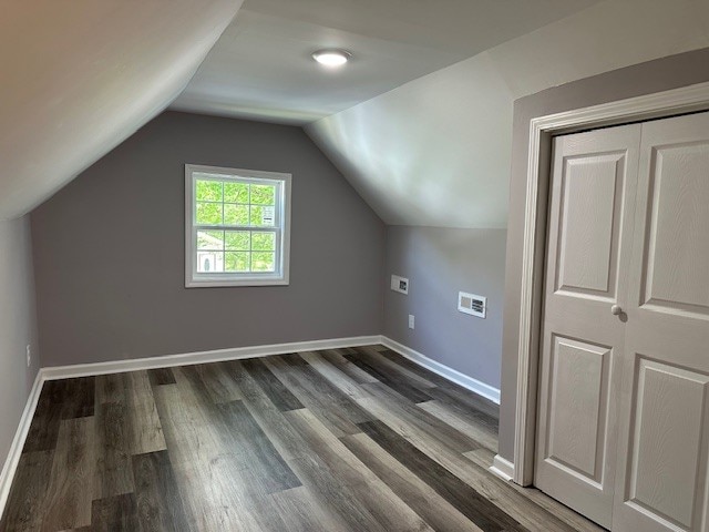 bonus room with lofted ceiling and dark wood-type flooring