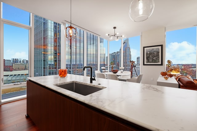 kitchen featuring a healthy amount of sunlight, wood-type flooring, decorative light fixtures, a notable chandelier, and sink